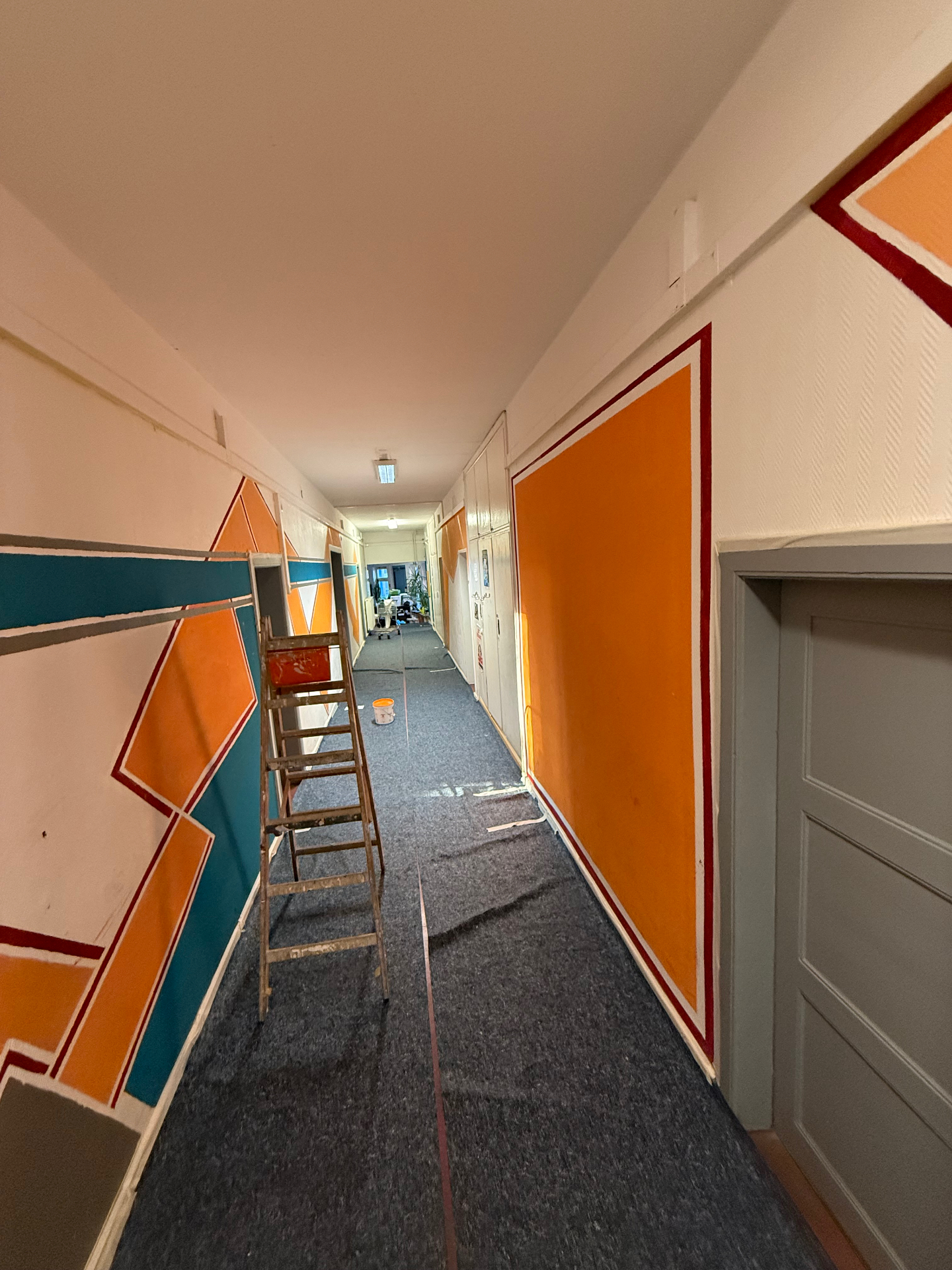 Ausgangssituation: Flur mit orange-türkiser geometrischer Wandgestaltung vor der Neugestaltung