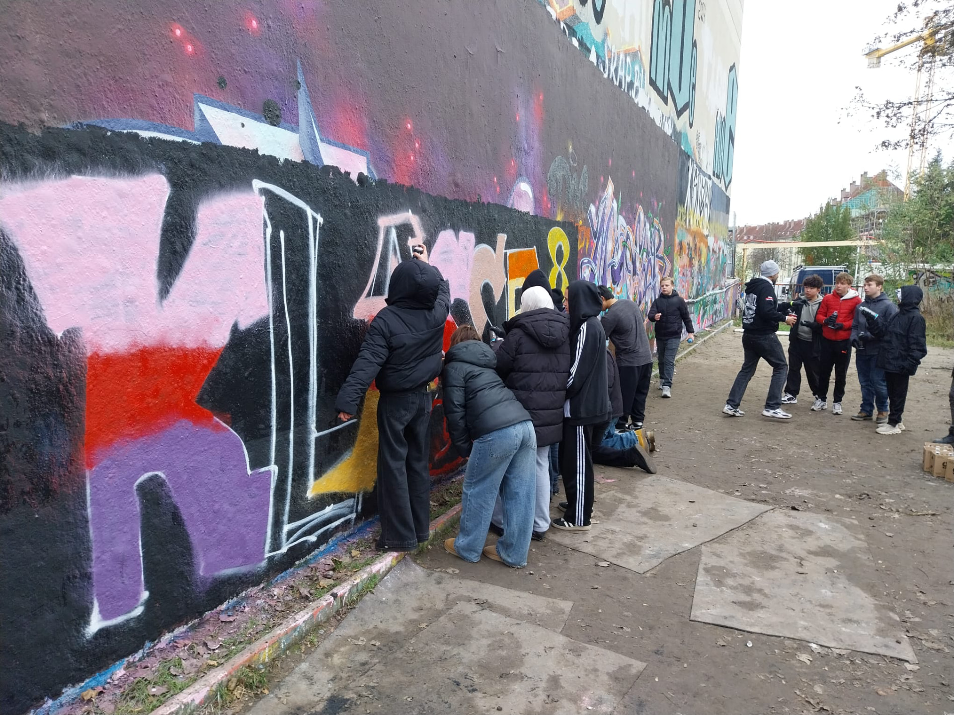 Gruppe arbeitet gemeinsam an einer großen Graffitiwand