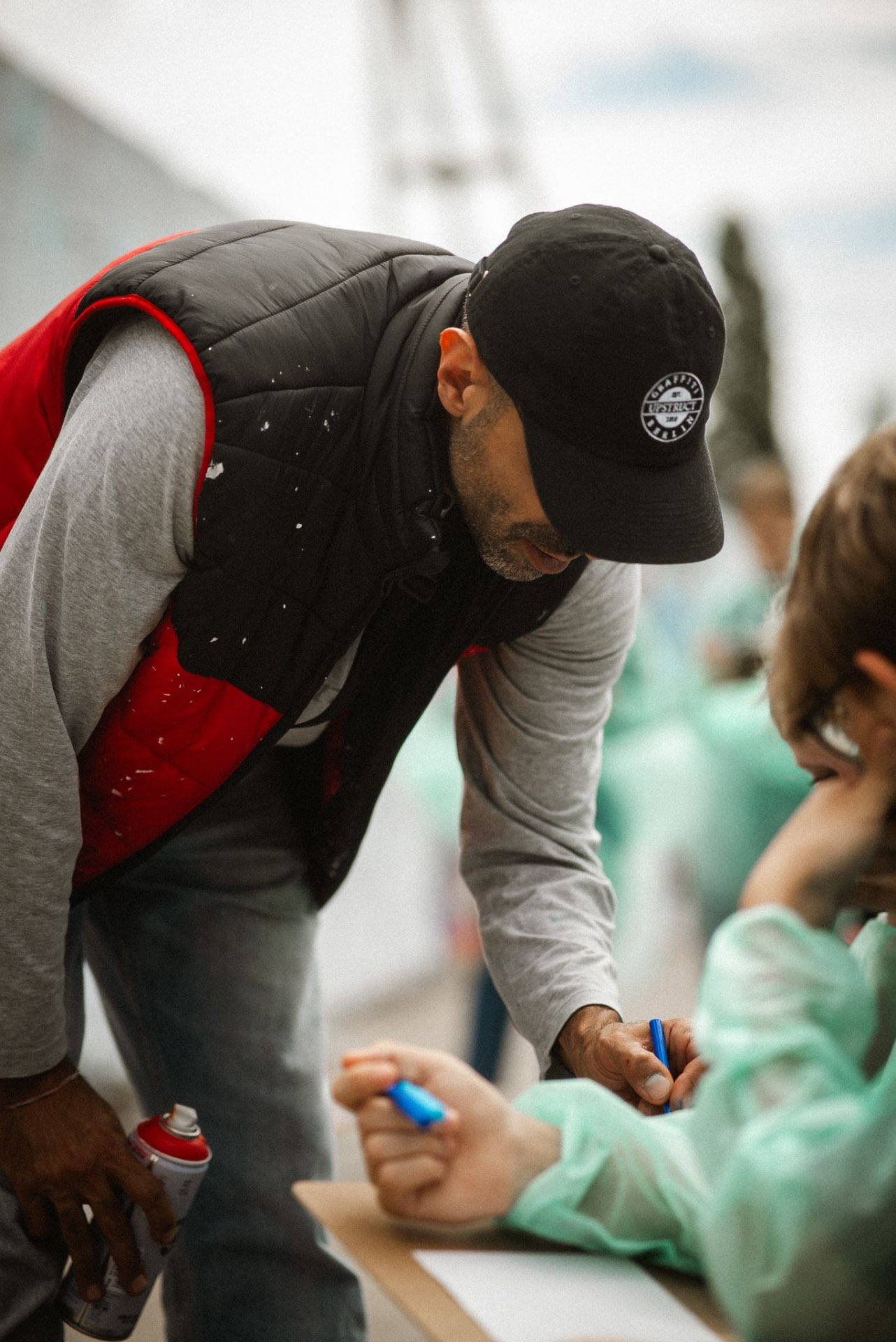 Baris unterstützt ein Kind beim kreativen Arbeiten im Workshop
