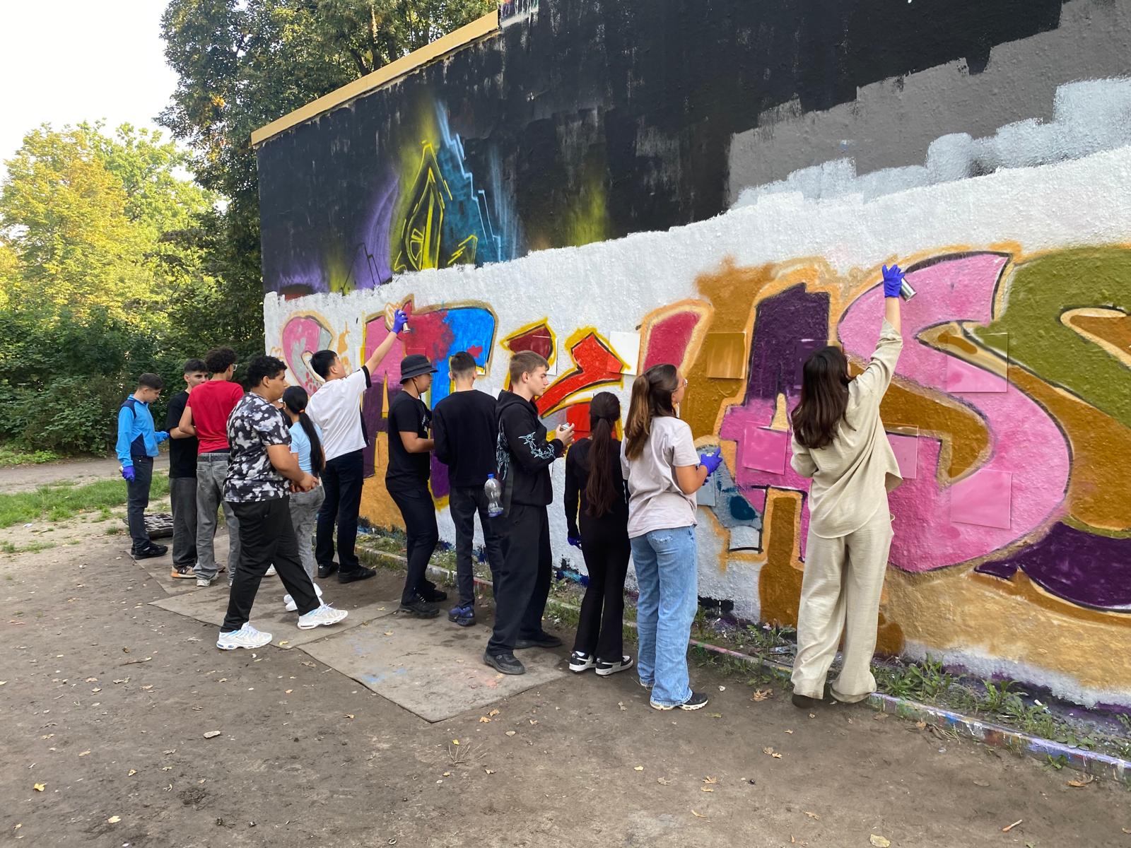 Jugendliche gestalten gemeinsam eine Graffitiwand bei einem WALLSTORIES-Workshop