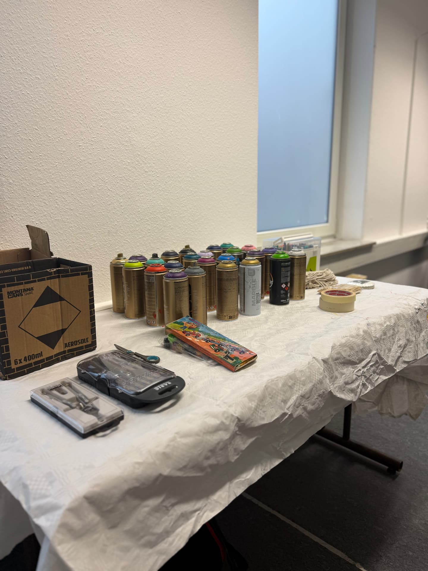 Spraydosen, Marker und Werkzeuge auf einem vorbereiteten Materialtisch