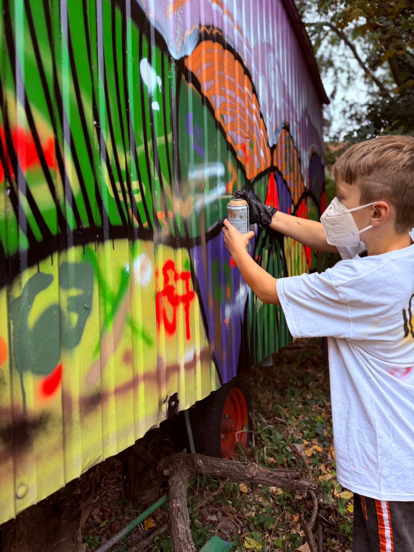 Junger Teilnehmer sprüht ein Mural auf einen Bauwagen